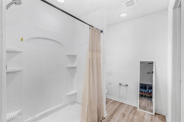 bathroom featuring hardwood / wood-style flooring, a shower with curtain, toilet, and a textured ceiling