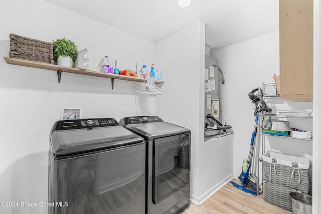 washroom featuring separate washer and dryer, light hardwood / wood-style floors, and a textured ceiling