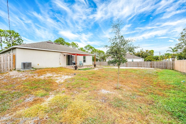 back of property featuring central AC and a lawn