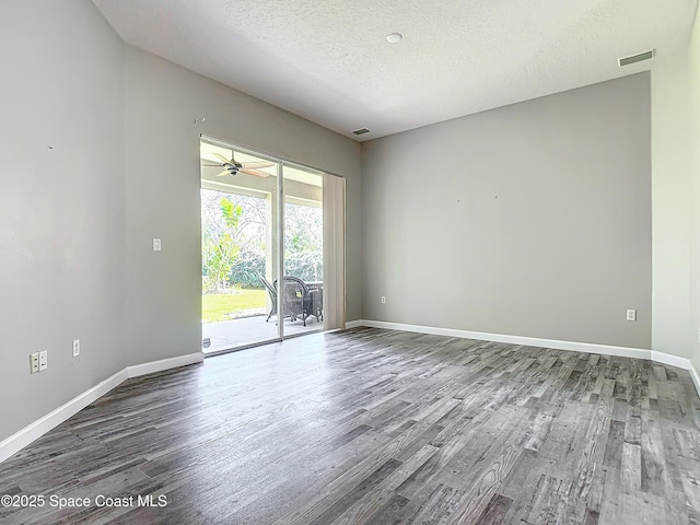 empty room with ceiling fan, dark hardwood / wood-style flooring, and a textured ceiling