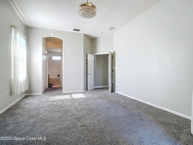 unfurnished bedroom with carpet flooring, a textured ceiling, and ensuite bathroom