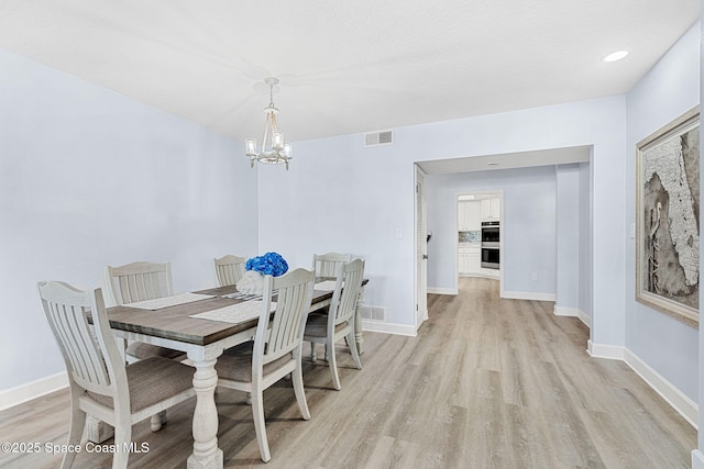 dining room with light hardwood / wood-style flooring and a notable chandelier