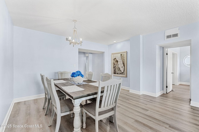 dining area featuring a chandelier, light wood-type flooring, and a textured ceiling