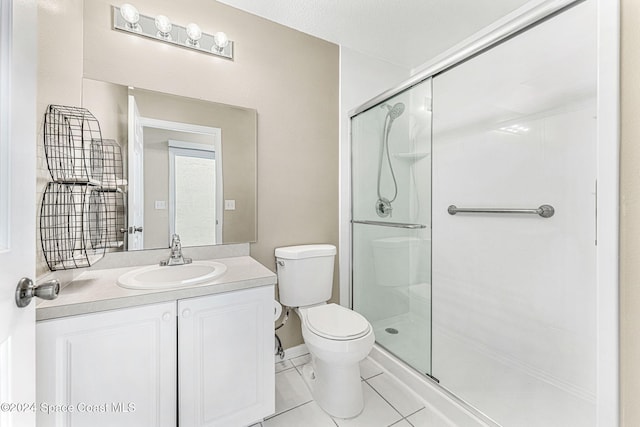 bathroom featuring toilet, vanity, tile patterned floors, and a shower with shower door