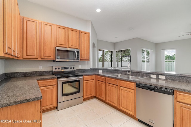 kitchen with kitchen peninsula, appliances with stainless steel finishes, ceiling fan, sink, and light tile patterned floors