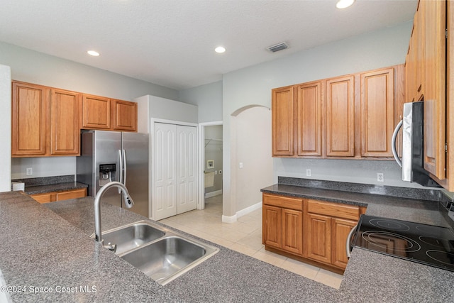 kitchen with sink, light tile patterned floors, stainless steel appliances, and a textured ceiling