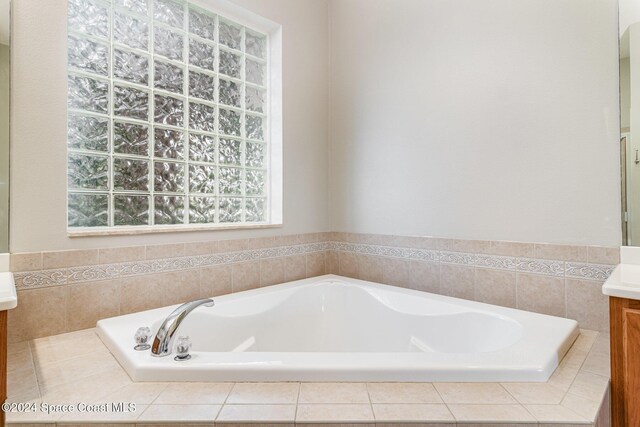 bathroom with tiled tub and vanity