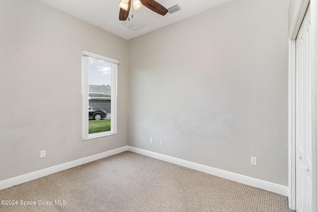 carpeted spare room featuring ceiling fan