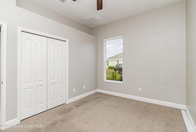 unfurnished bedroom featuring light carpet, a closet, and ceiling fan