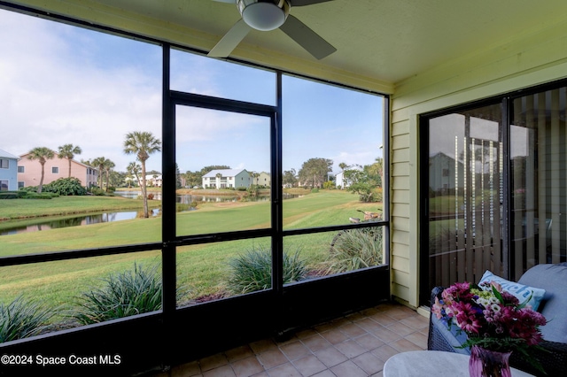 sunroom / solarium with ceiling fan and a water view