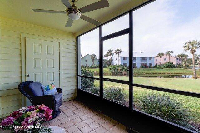 sunroom with ceiling fan and a water view