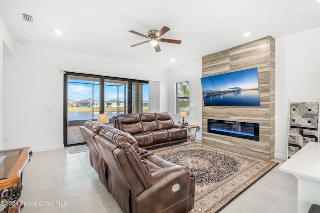 living room with a tile fireplace, ceiling fan, and light tile patterned floors