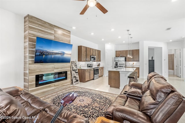 living room featuring ceiling fan, a fireplace, light tile patterned flooring, and sink