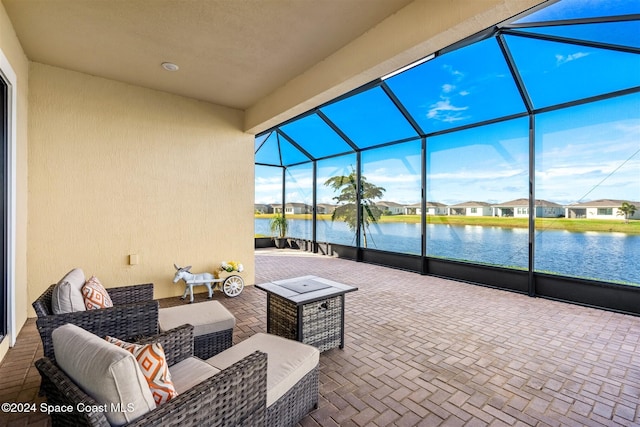 view of patio / terrace featuring glass enclosure, a water view, and an outdoor living space