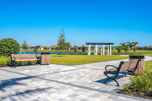 surrounding community with a water view, a pergola, and a yard