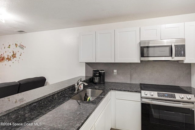 kitchen with dark stone countertops, white cabinetry, sink, and appliances with stainless steel finishes