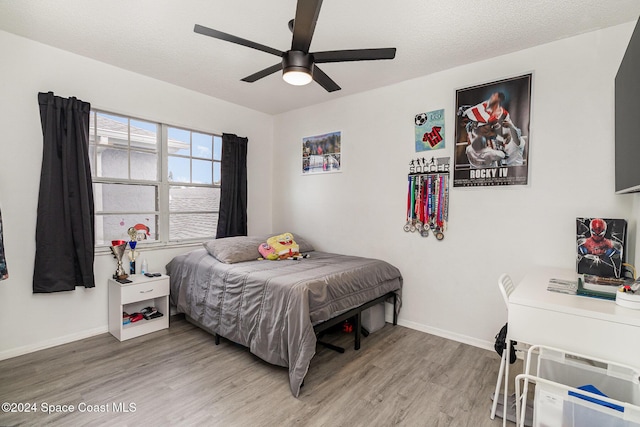 bedroom featuring ceiling fan, wood-type flooring, and a textured ceiling