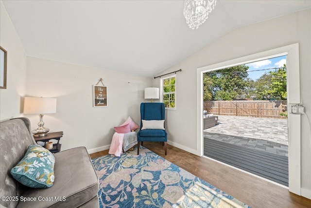 living area featuring hardwood / wood-style floors, lofted ceiling, and a notable chandelier