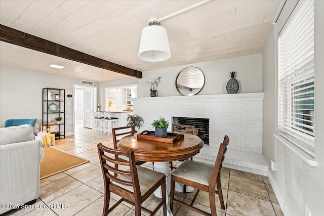 tiled dining room with beamed ceiling and a brick fireplace