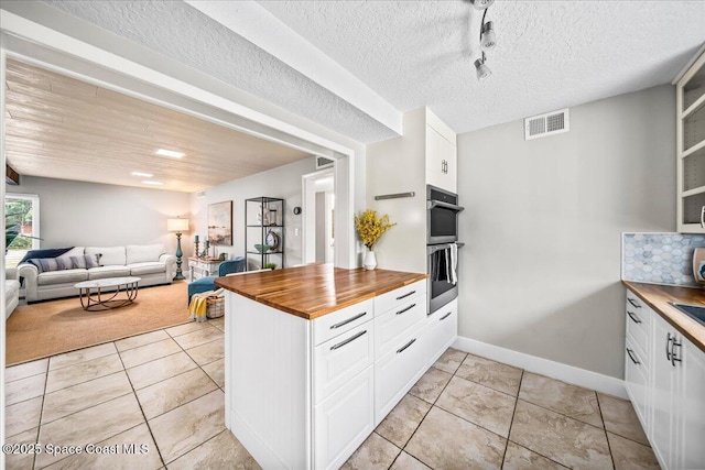 kitchen with tasteful backsplash, white cabinetry, and wooden counters