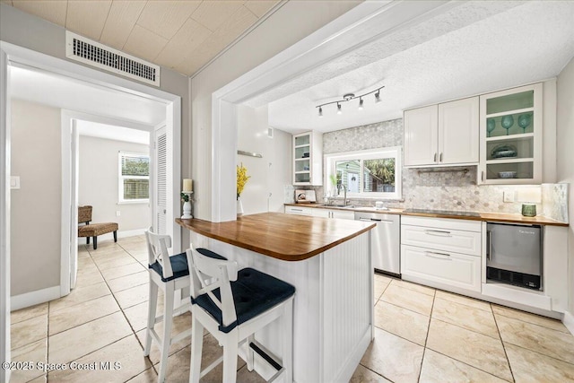 kitchen featuring dishwasher, wooden counters, white cabinets, sink, and a healthy amount of sunlight