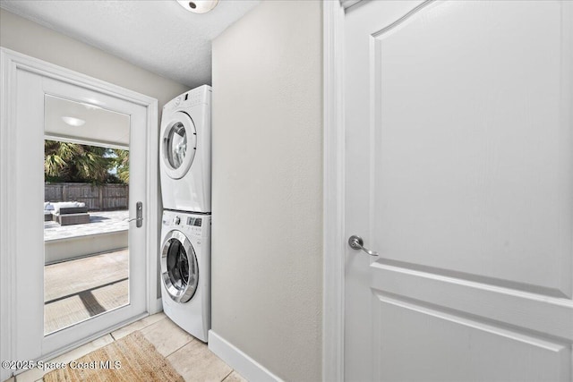 washroom featuring light tile patterned floors, a textured ceiling, and stacked washer and clothes dryer