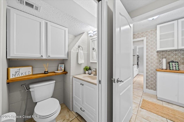 bathroom featuring tile patterned flooring, vanity, a textured ceiling, and toilet