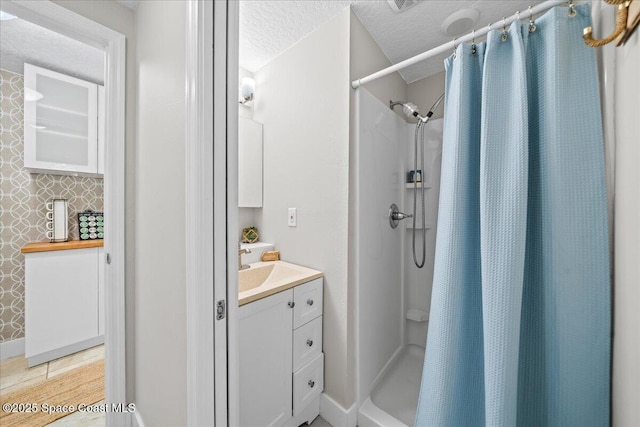 bathroom with a shower with shower curtain, vanity, backsplash, and a textured ceiling