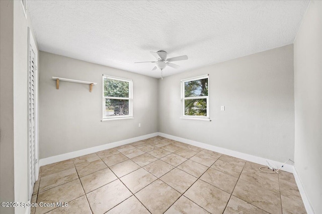 empty room featuring ceiling fan, light tile patterned flooring, and a textured ceiling