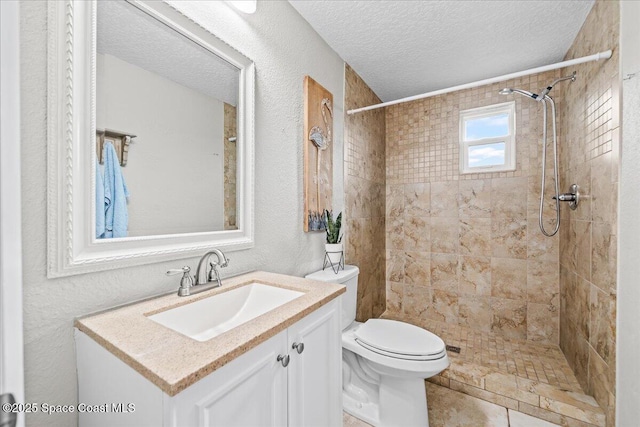 bathroom with vanity, tile patterned floors, toilet, a textured ceiling, and a tile shower