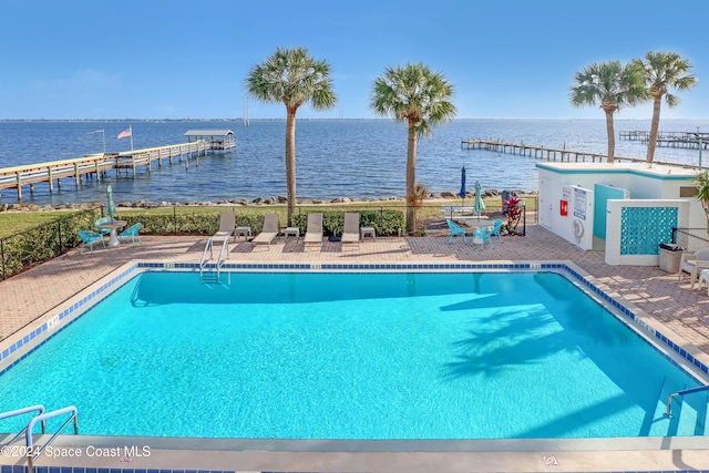 view of pool featuring a water view, a dock, and a patio area