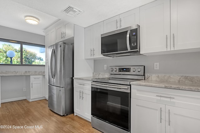 kitchen with white cabinetry, light hardwood / wood-style floors, a textured ceiling, and appliances with stainless steel finishes