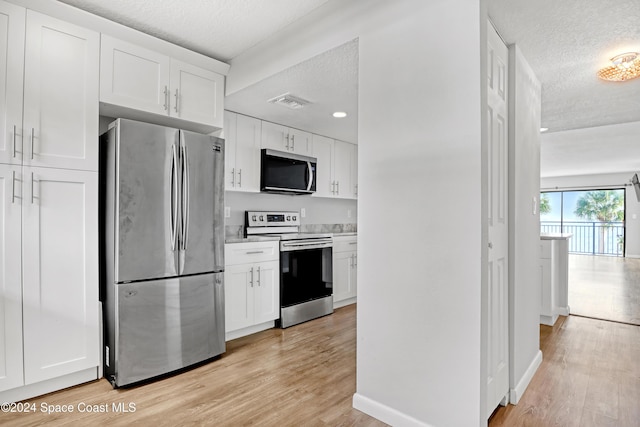 kitchen featuring light hardwood / wood-style floors, white cabinetry, a textured ceiling, and appliances with stainless steel finishes