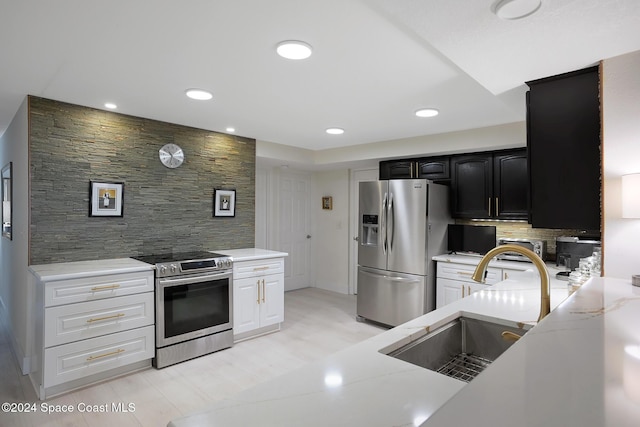 kitchen with white cabinets, sink, decorative backsplash, light stone countertops, and stainless steel appliances