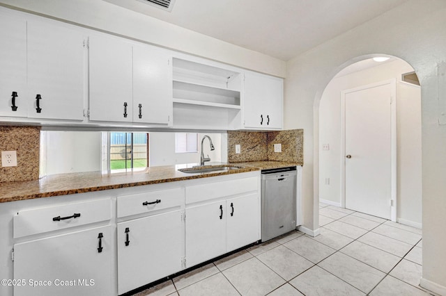 kitchen featuring stainless steel dishwasher, dark stone countertops, white cabinetry, and backsplash