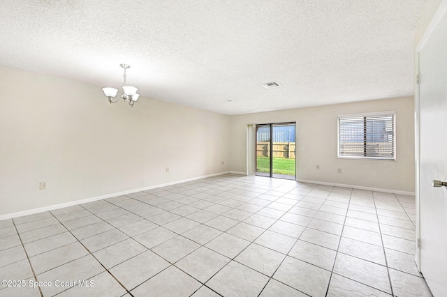 tiled empty room with a notable chandelier and a textured ceiling