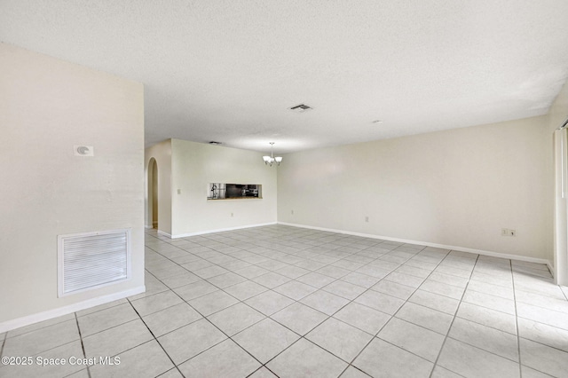 unfurnished living room with light tile patterned floors, a chandelier, and a textured ceiling