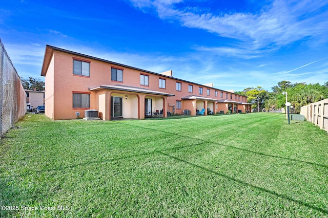 rear view of house featuring a lawn and central AC