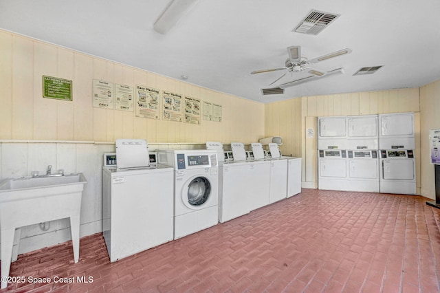 washroom featuring ceiling fan, wood walls, washer and dryer, and stacked washer / drying machine