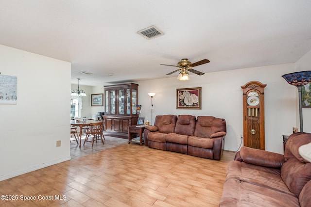 living room with ceiling fan with notable chandelier and light hardwood / wood-style floors