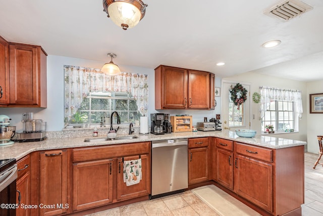 kitchen featuring kitchen peninsula, light stone counters, sink, and appliances with stainless steel finishes