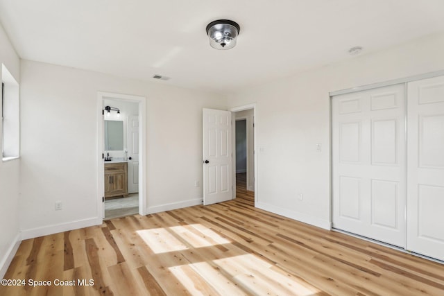 unfurnished bedroom with connected bathroom, a closet, and light hardwood / wood-style floors