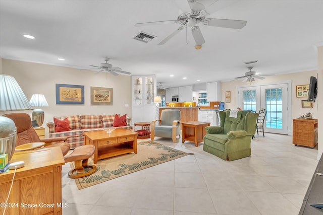 living room with crown molding, french doors, and light tile patterned floors