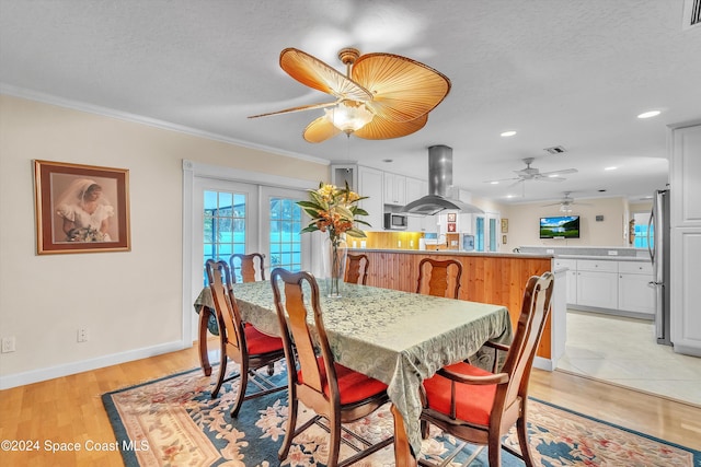 dining area with a textured ceiling, light hardwood / wood-style floors, and crown molding