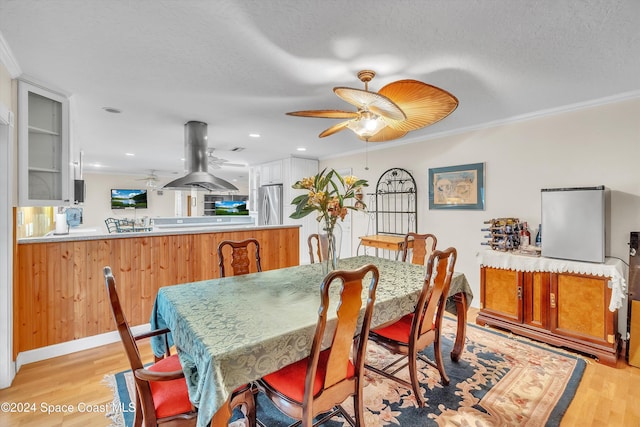 dining space with a textured ceiling, light wood-type flooring, and crown molding