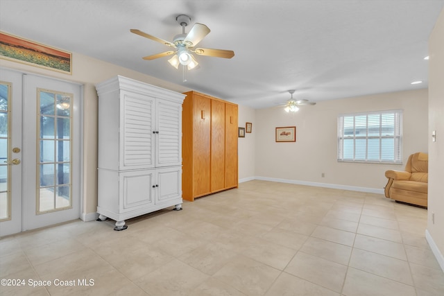 unfurnished living room featuring ceiling fan, french doors, and light tile patterned flooring