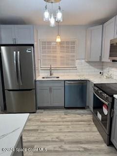 kitchen featuring appliances with stainless steel finishes, gray cabinets, hanging light fixtures, and sink