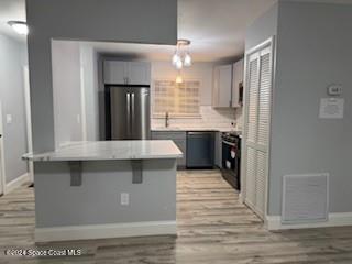 kitchen featuring gray cabinetry, a kitchen breakfast bar, light hardwood / wood-style flooring, pendant lighting, and black appliances