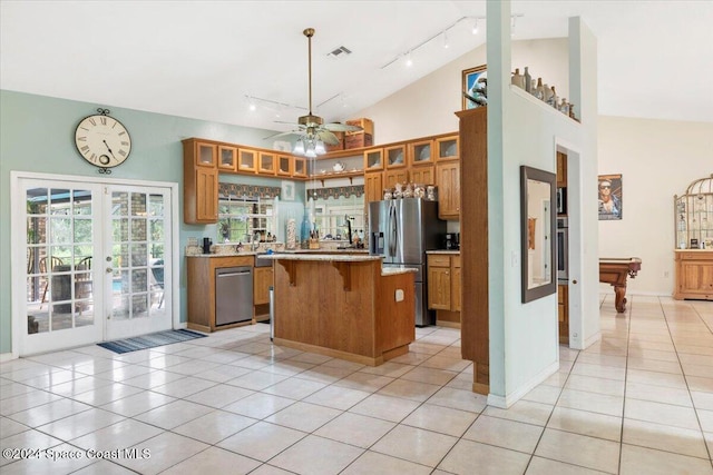 kitchen featuring a center island, stainless steel appliances, track lighting, a kitchen bar, and light tile patterned flooring