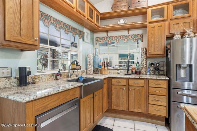 kitchen featuring light stone countertops, stainless steel fridge with ice dispenser, sink, and light tile patterned floors